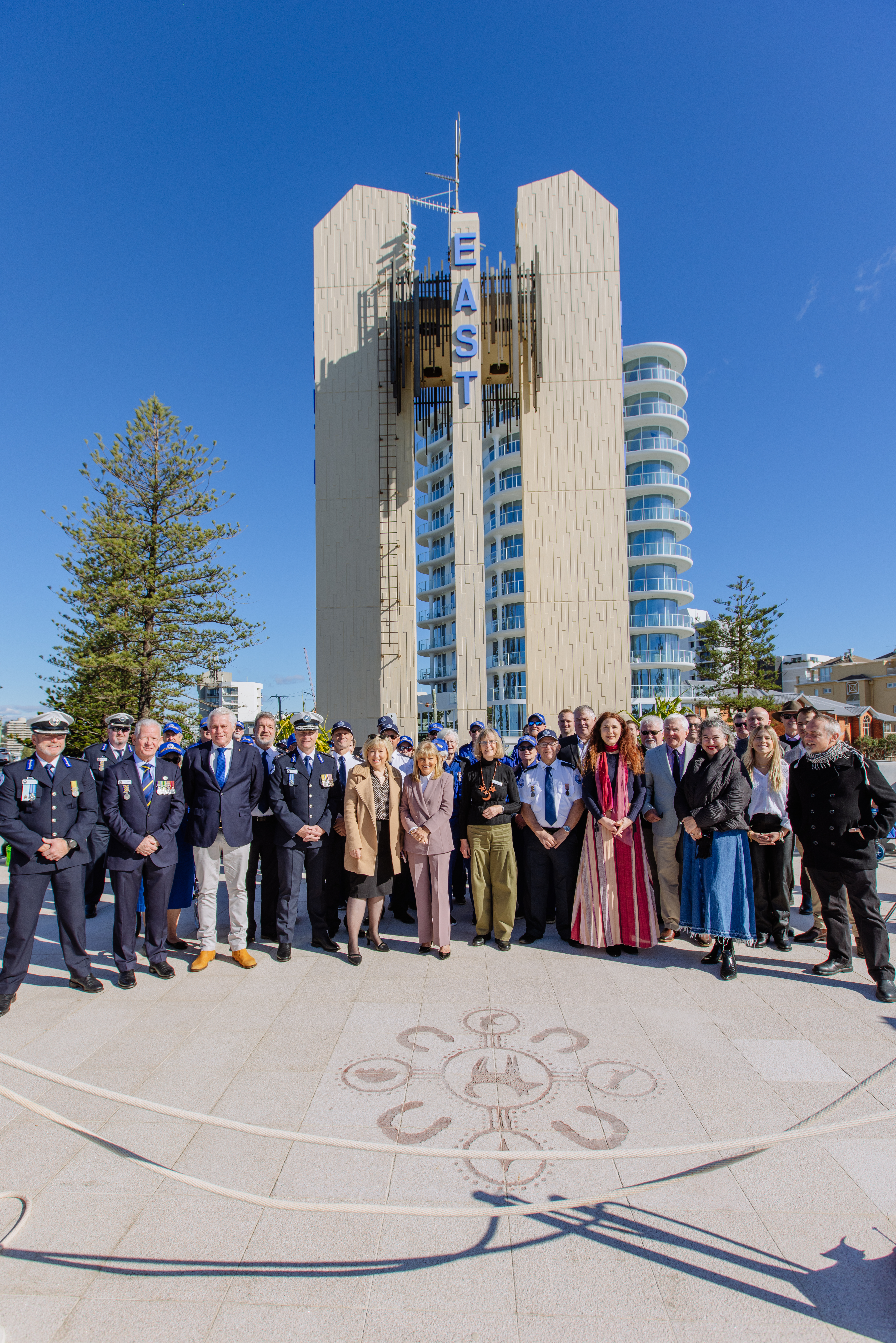 Project team standing in front of the newly refurbished Captain Cook Memorial and Lighthouse at Tweed Heads with the structure in the background and a Connection to Country artwork on the concrete in front.